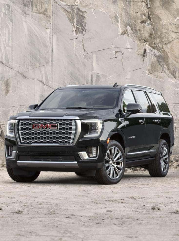 A black GMC Yukon parked off-road.