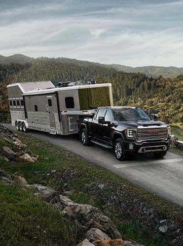 A black 2023 GMC Sierra towing a camper.