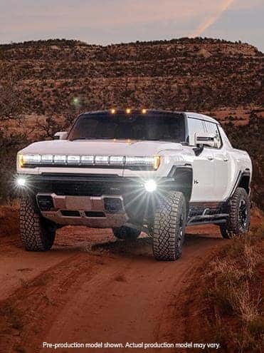 A white 2023 GMC Hummer EV driving off-road.