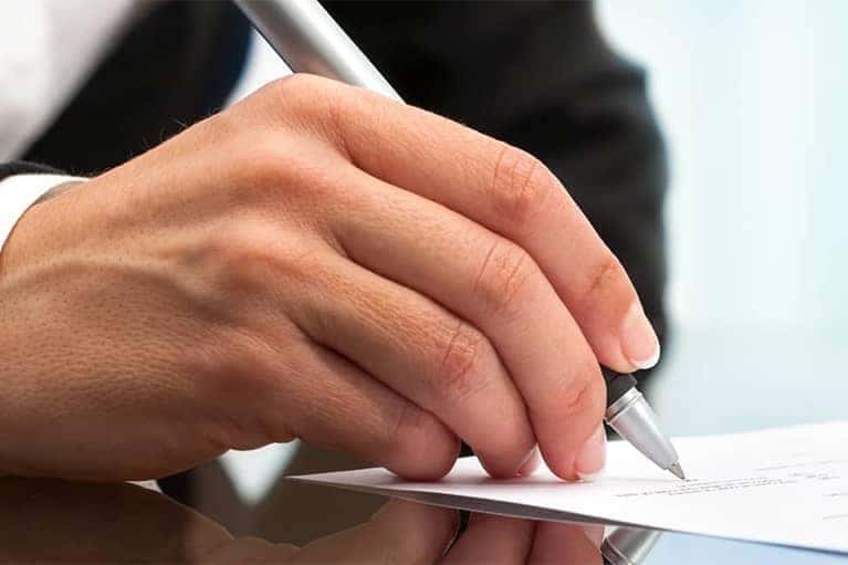 Hands of Man Holding Pen Signing Document