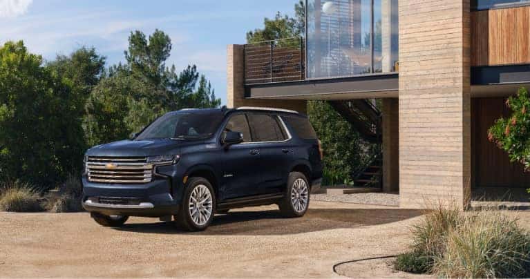 A blue Chevy Tahoe parked outside of a house