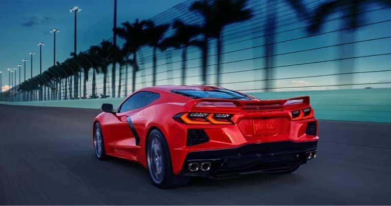 A Chevy Corvette driving on a road at night with palm trees in the background