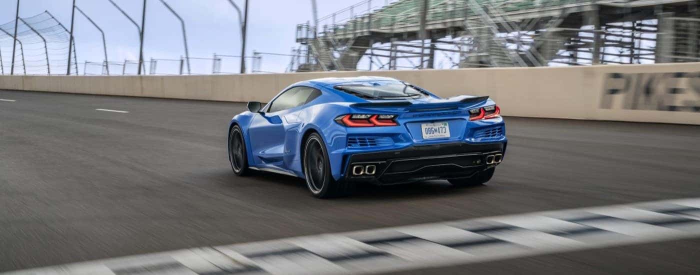 A blue 2024 Chevy Corvette E-Ray 3LZ is shown crossing a finish line.
