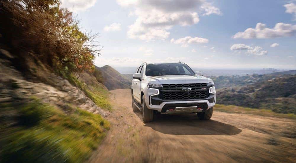 A white 2021 Chevy Tahoe Z71 on a dusty trail after leaving a used Chevy dealer.