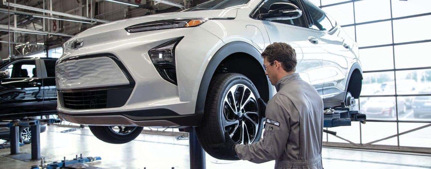 A tech is shown working on a grey 2023 Chevy Bolt EUV on a lift.