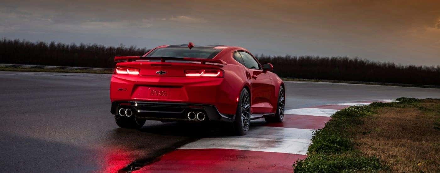 A red 2018 Chevy Camaro ZL1 is shown from behind driving on a race track.