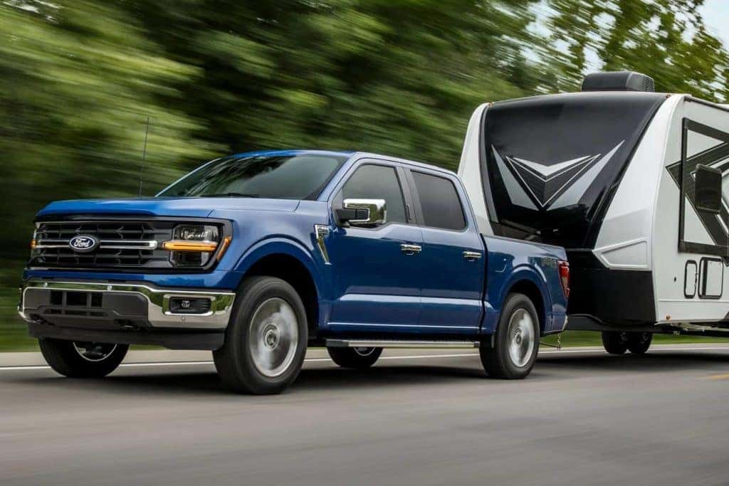A blue 2024 Ford F-150 towing a trailer.