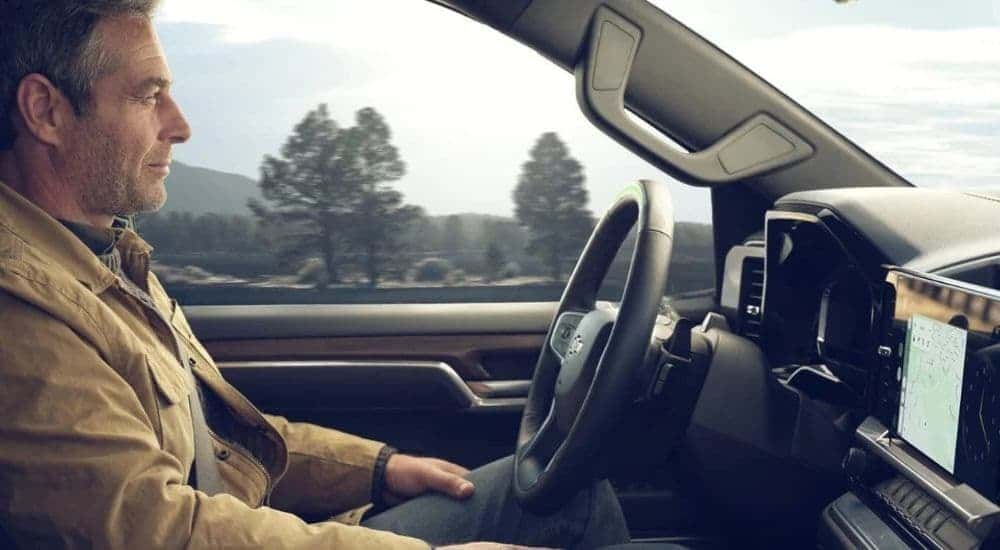 A person driving in a used 2024 Chevy Silverado for sale near Houston.