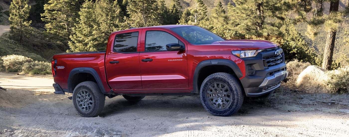 Side angle view of a red 2024 Chevy Colorado Trail Boss parked off-road.