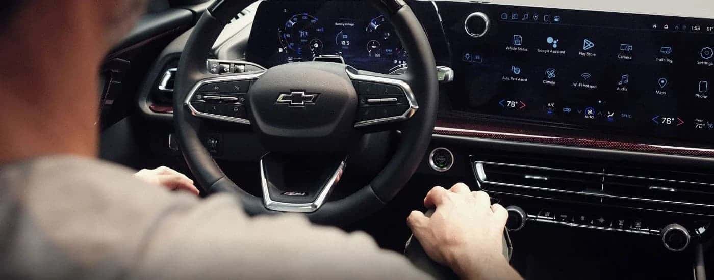 A man sitting in the front seat in the black interior of a 2024 Chevy Traverse Z71.