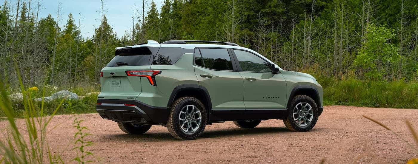 Rear right angle view of a green 2025 Chevy Equinox ACTIV for sale parked off-road.