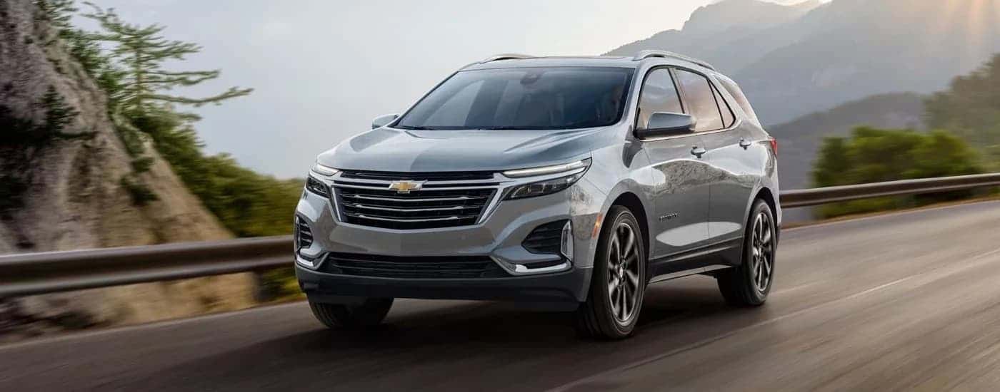 Grey 2023 Chevy Equinox for sale near Houston driving down a road.