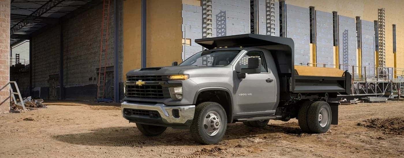 A grey 2024 Chevy Silverado 3500 HD Chassis Cab in front of a building.