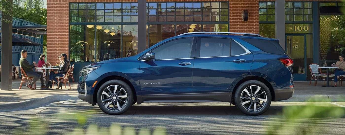 Side angle view of a blue 2022 Chevy Equinox parked by a curb.
