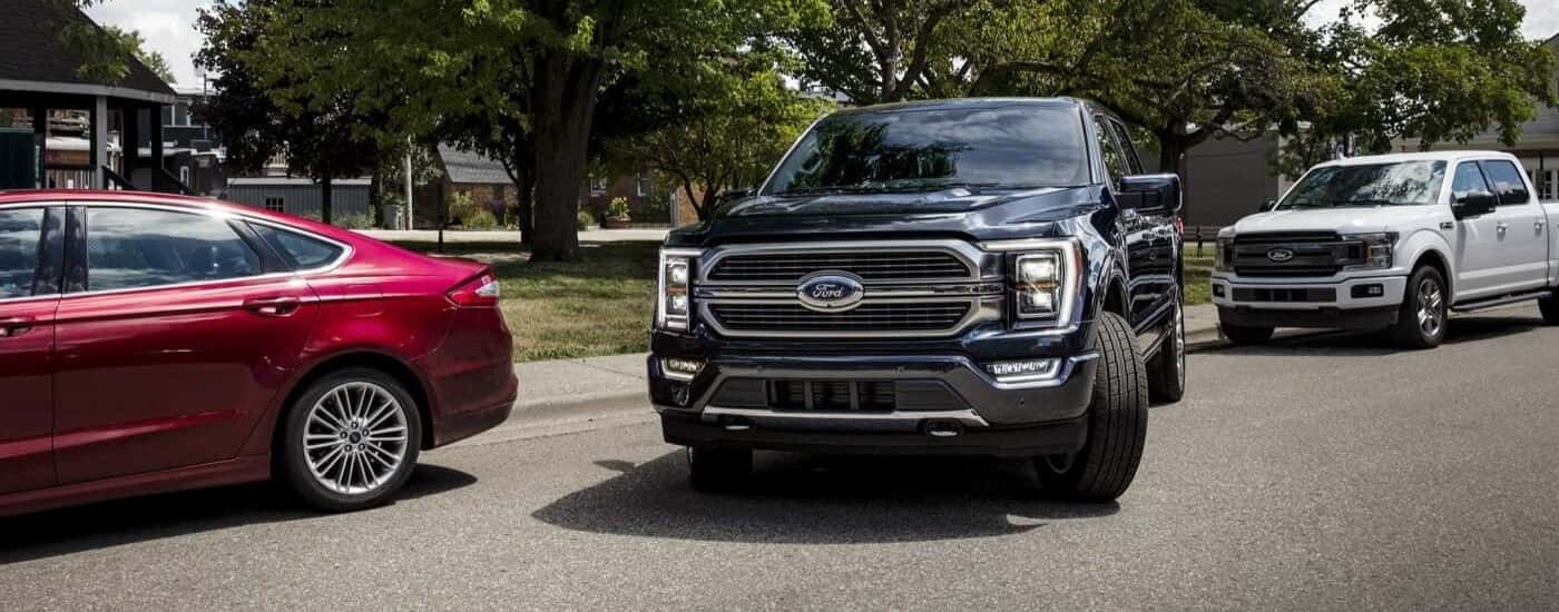 A black 2023 Ford F-150 pulling away from a curb near a dealer with used trucks for sale in Tomball.