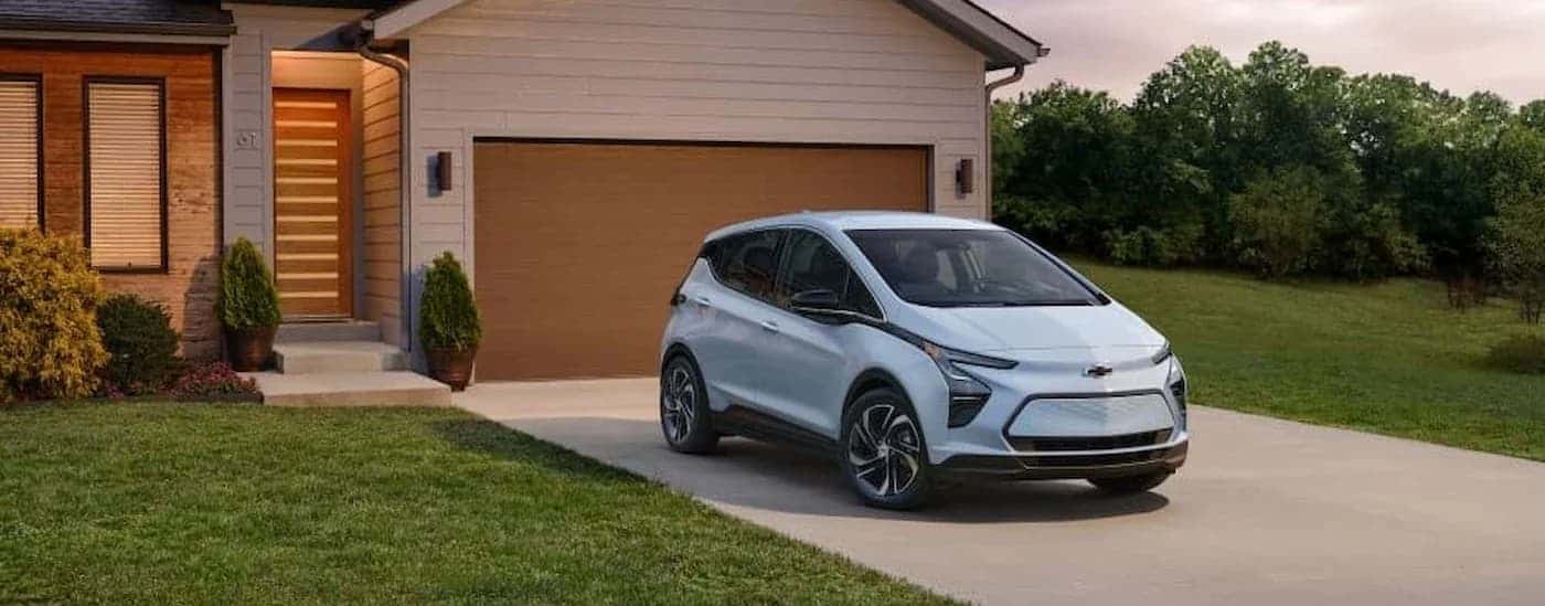 A light blue 2023 Chevy Bolt EV parked on a driveway.
