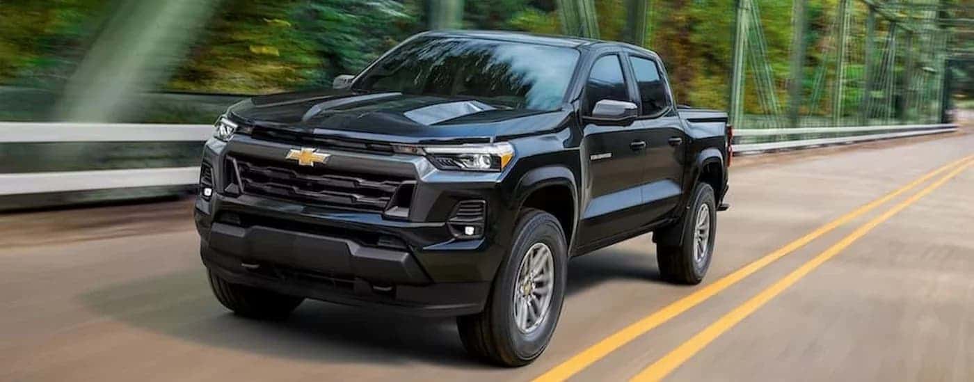A black 2023 Chevy Colorado driving to view used cars for sale near Houston.