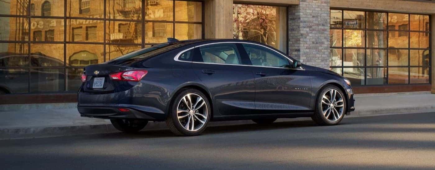 A black 2023 Chevy Malibu parked outside a building in a city