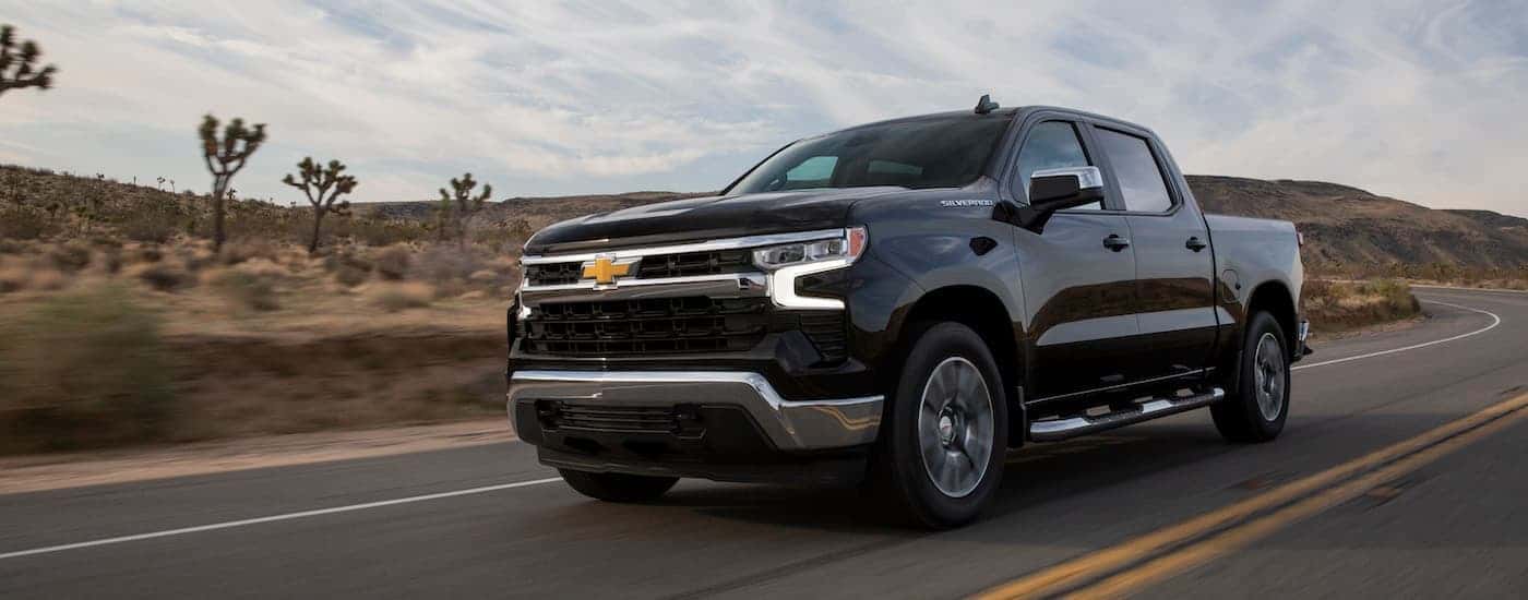 A black 2022 Chevy Silverado 1500 LT is shown from the front at an angle after leaving a dealer that has used trucks for sale near the Woodlands.