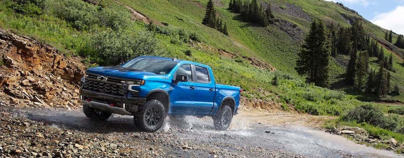 A blue 2024 Chevy Silverado 1500 ZR2 is shown from the front at an angle after leaving a dealer that has Chevy trucks for sale near Houston.