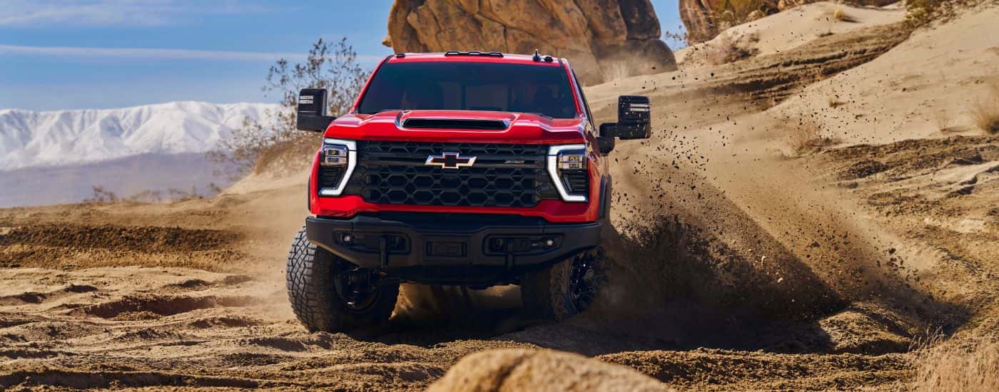 A red 2024 Chevy Silverado 2500 HD ZR2 Bison is shown kicking up dust.