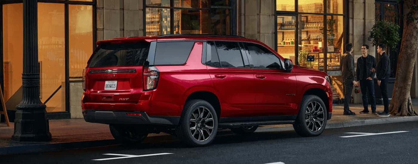 A red 2023 Chevy Tahoe RST is shown from the side while parked on a city street