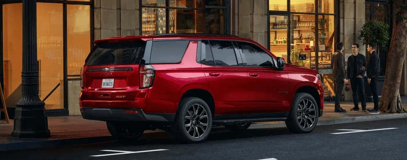 A red 2023 Chevy Tahoe RST is shown from the side while parked on a city street.