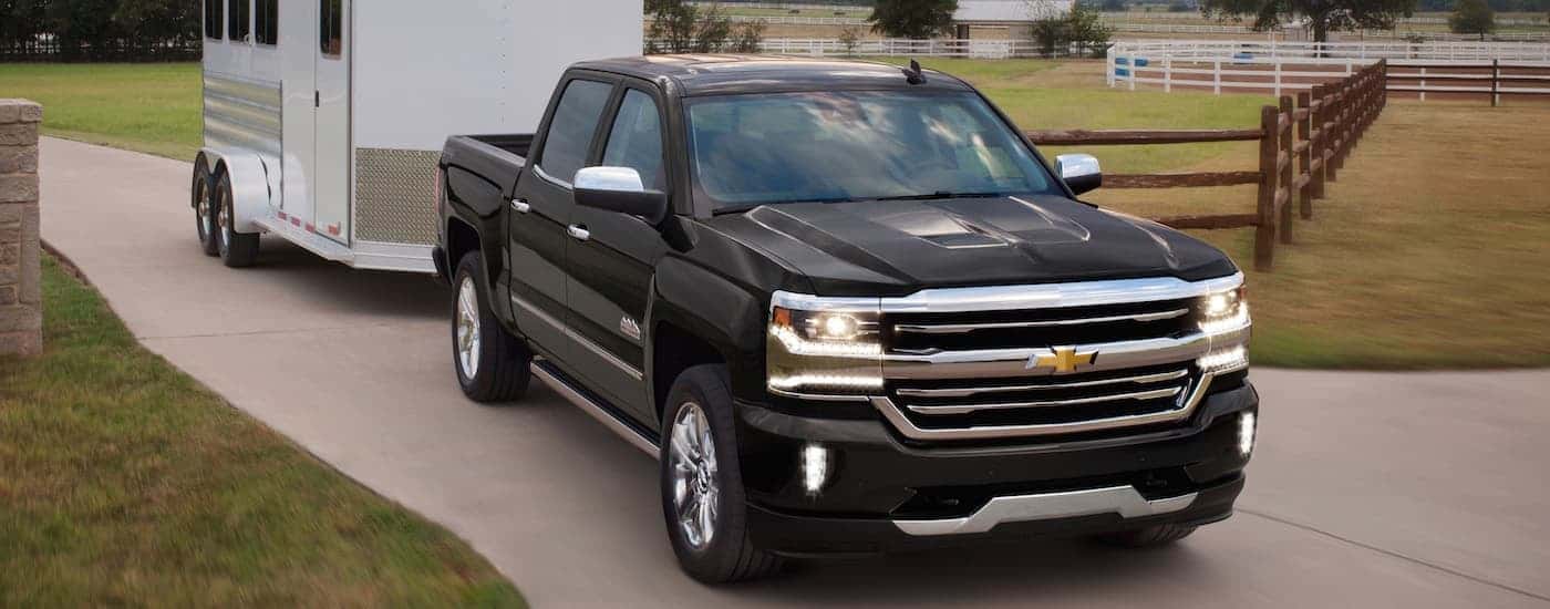 A black 2018 Chevy Silverado 1500 is shown towing a trailer.