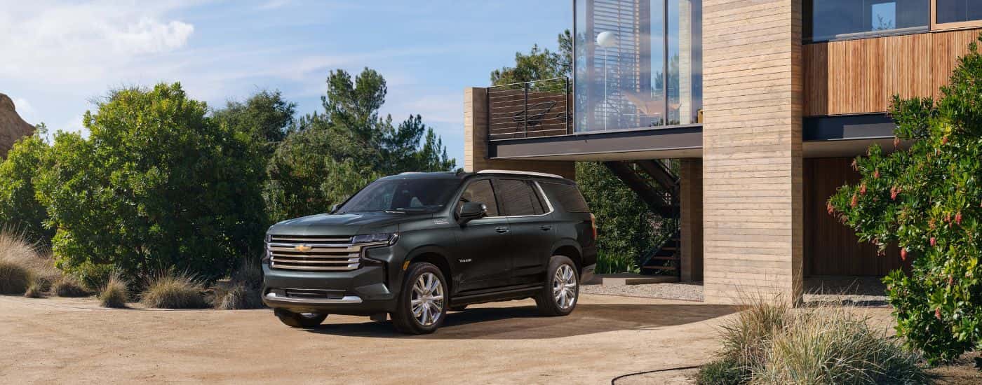 A grey 2022 Chevy Tahoe High Country is shown in front of a modern house.