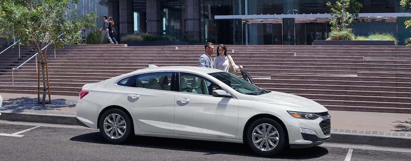 A white 2022 Chevy Malibu is shown from the side parked in a city.