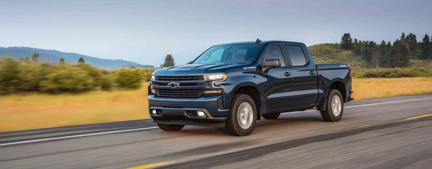 A blue 2020 Chevy Silverado 1500 is shown driving on an open road