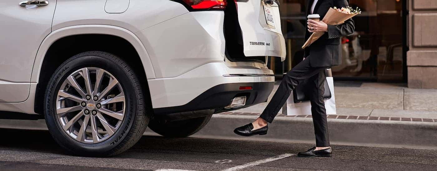 A person is shown opening the lift-gate on a white 2022 Chevy Traverse