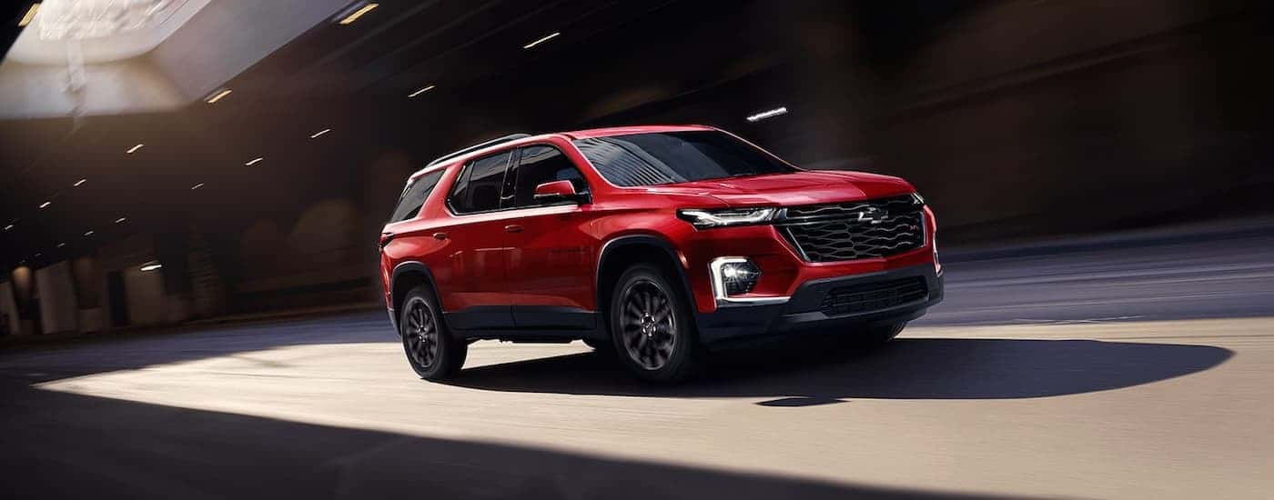 A red 2022 Chevy Traverse RS is shown driving on a city street