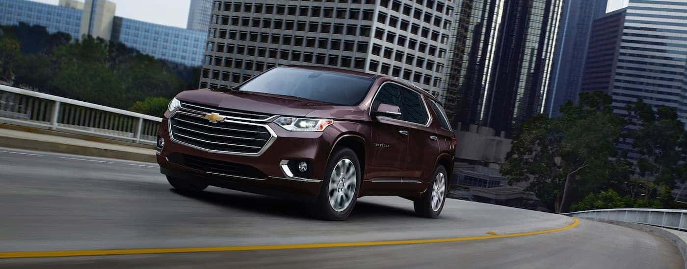 A maroon used 2020 Chevy Traverse for sale near The Woodlands is shown during a test drive on a highway