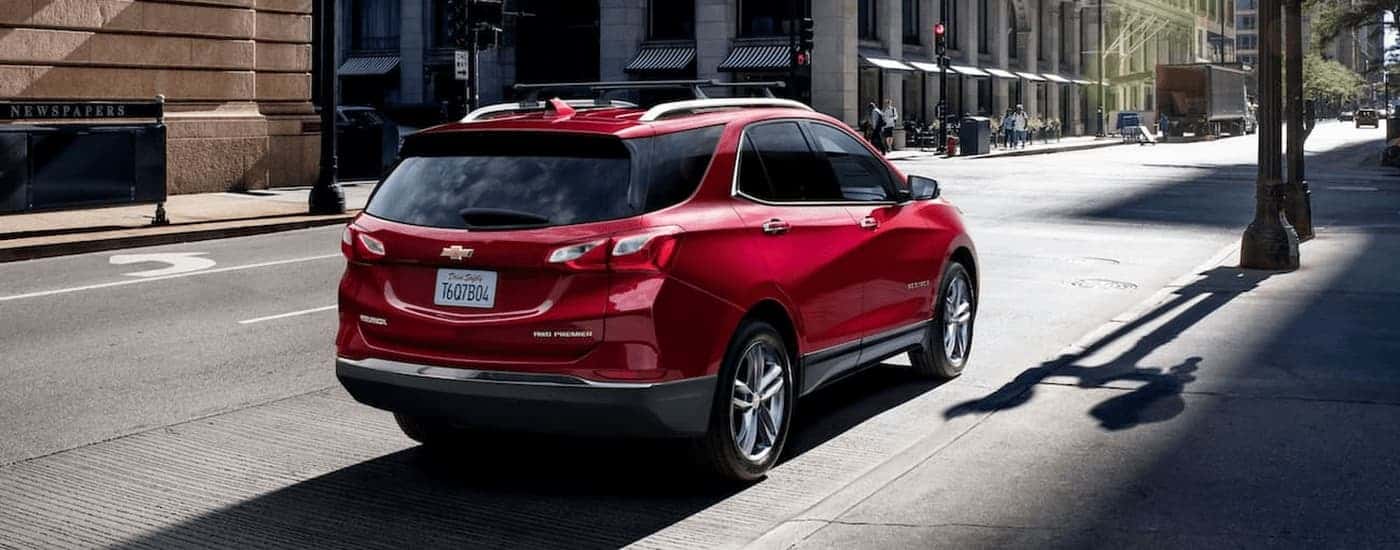 A red 2021 Chevy Equinox is shown from the rear parked on the side of a city street