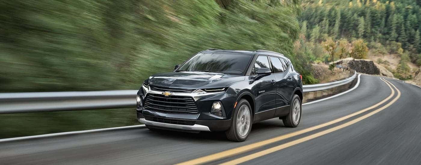 A black 2022 Chevy Blazer is shown driving on an open road after viewing used SUVs for sale