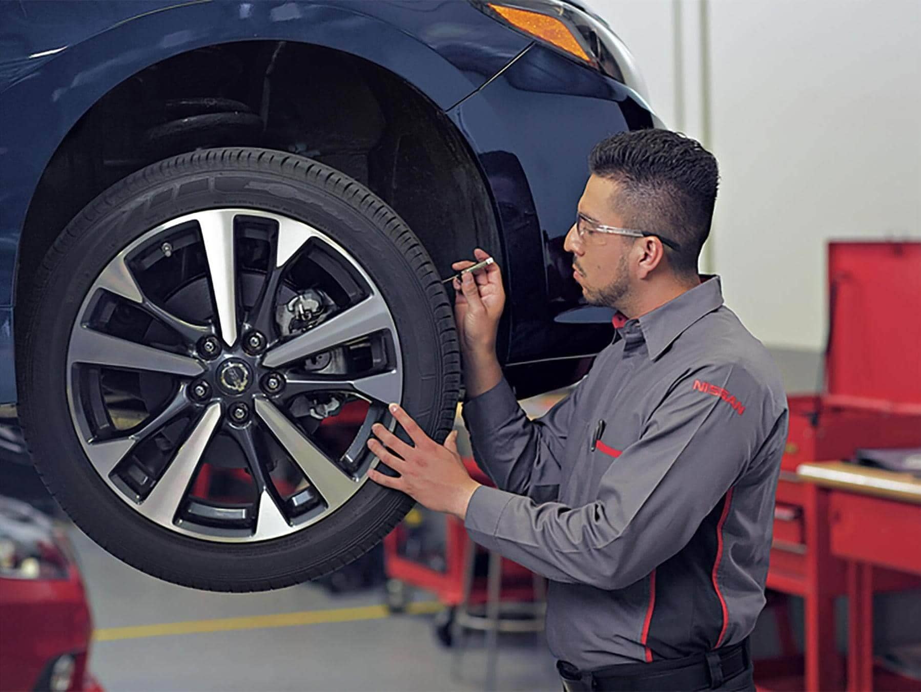 Nissan Service technician testing the tire treads on a vehicle