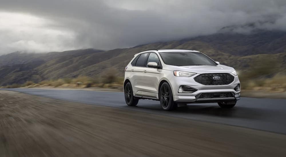A white 2022 Ford Edge ST is shown from the front driving on an open road.
