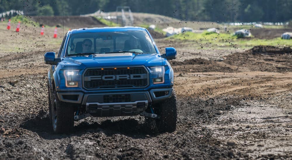 A blue 2017 Ford Raptor is shown from the front off-roading.