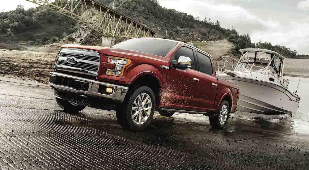 A red 2018 Ford F-150 is shown from the front while towing a boat out of water.