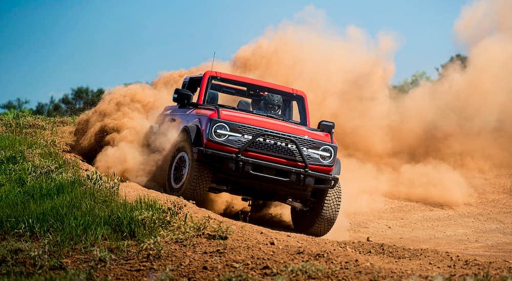A red 2021 Ford Bronco Wildtrak is shown from the front at an angle while off-road.