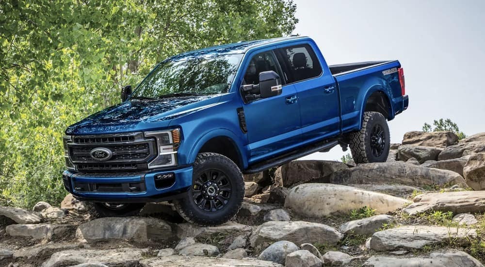 A blue 2022 Ford F-250 is shown parked on rocks.