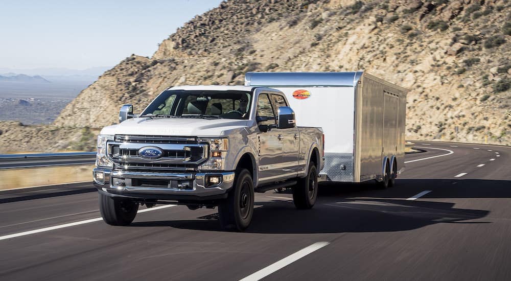 A white 2021 Ford F-250 is shown from the front while towing a trailer.