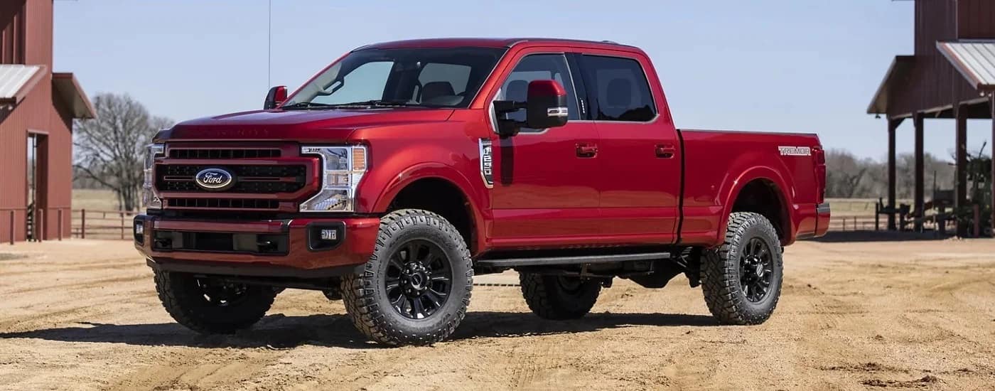 A red 2022 Ford F-250 Lariat is shown from the side on a ranch.