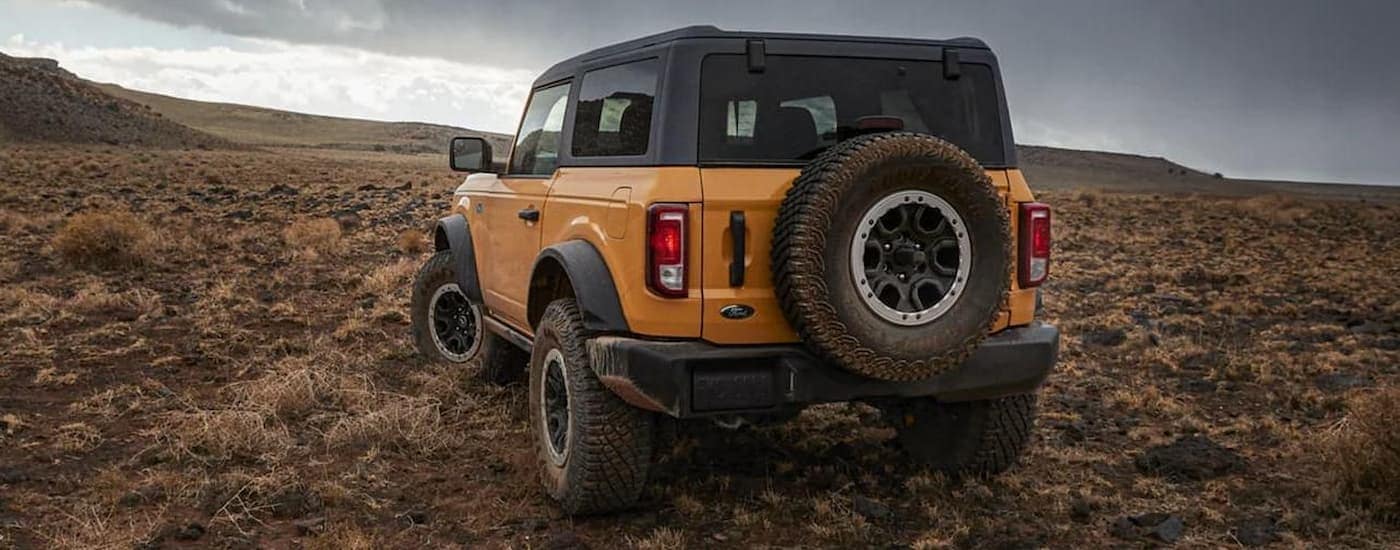 A yellow 2021 Ford Bronco is shown from the rear parked in a desert.