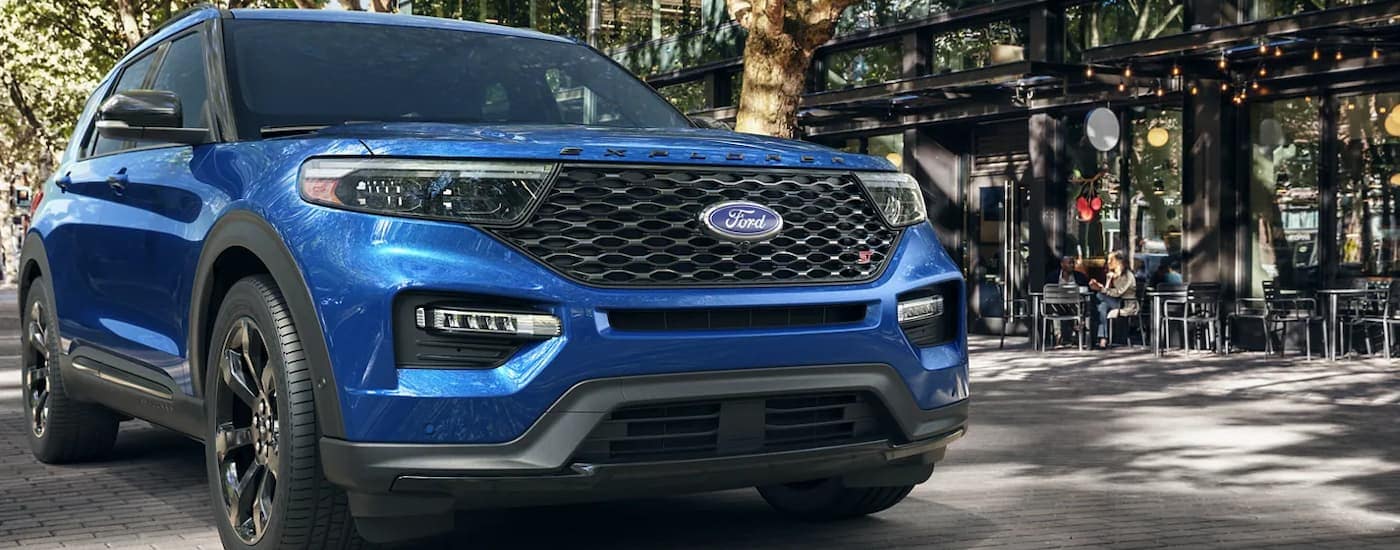 A blue 2022 Ford Explorer ST is shown parked outside of a small city cafe.