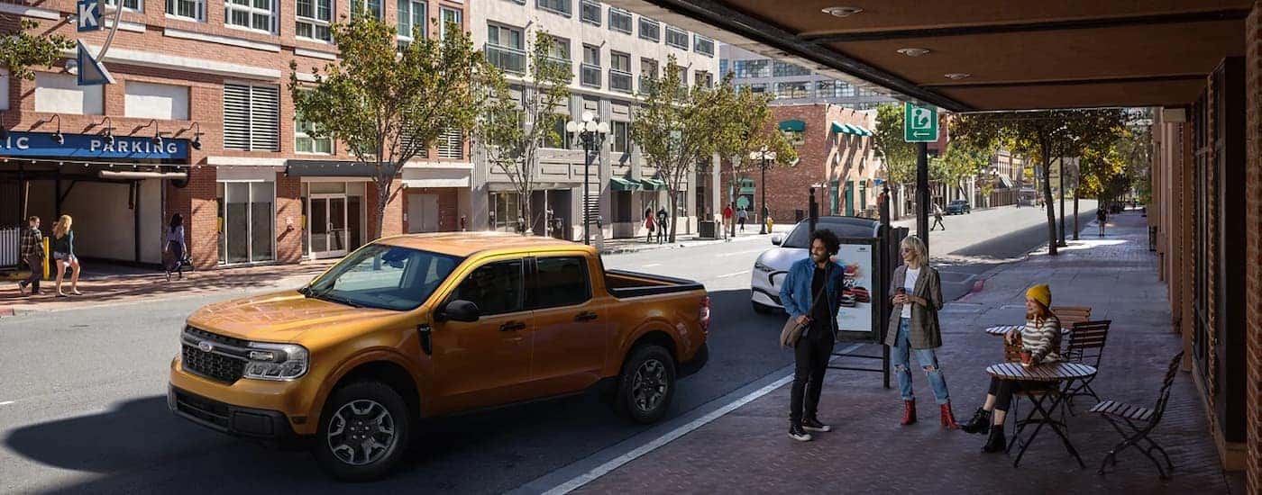 An orange 2022 Ford Maverick is shown from the side on a city street.