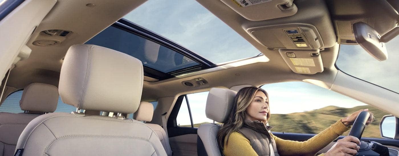 The tan interior of a 2022 Ford Explorer shows a person driving to a used car dealer near you.