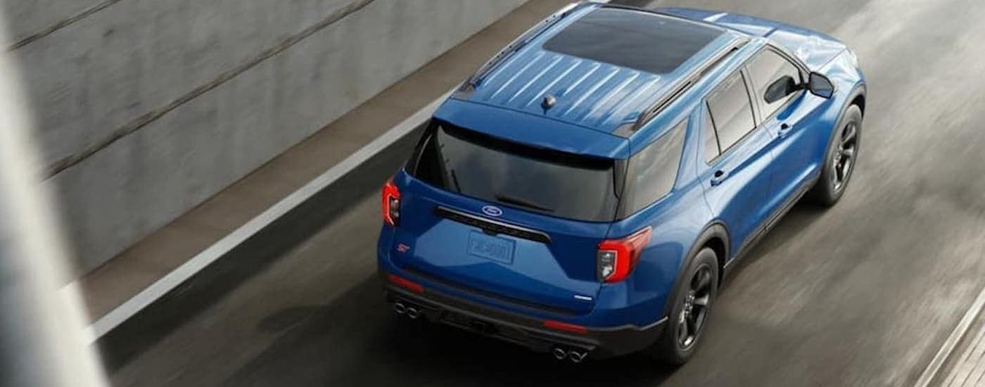 A blue 2020 Ford Explorer is shown from above driving on an open highway after leaving a used Ford dealership.