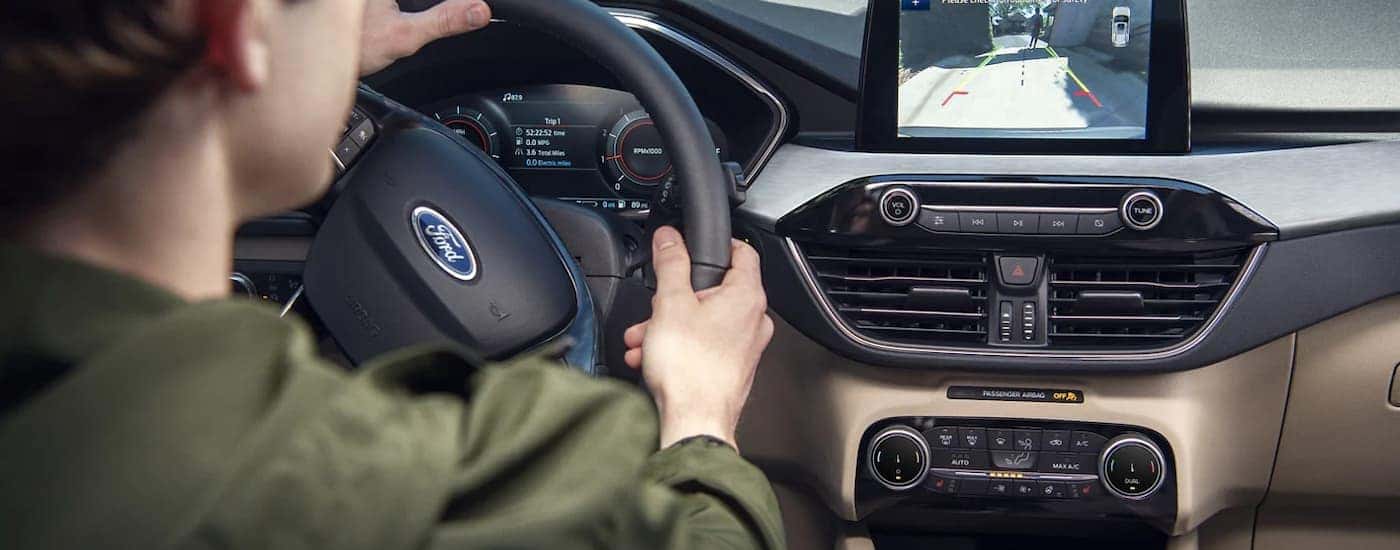 A person is shown testing the back-up camera in a used 2022 Ford Escape for sale.